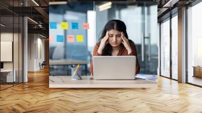 Upset and tired woman sitting at workplace inside office, business woman leaning on arms reading electronic report, company worker unhappy with team work result. Wall mural