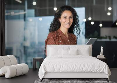 Young and successful female programmer, portrait of female engineer with tablet computer startup worker working inside office building using tablet for testing applications smiling looking at camera. Wall mural