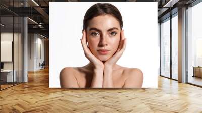 Beautiful young woman with clean perfect skin. Portrait of beauty model with natural nude make up and touching her face. Spa, skincare and wellness. Close up, white background, copyspace Wall mural