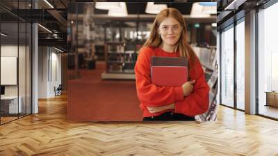 Education, learning and personal growth concept. Attrative redhead girl student visit library, pick books to read or study for classes, librarian, bookstore employee work part-time, smiling camera Wall mural