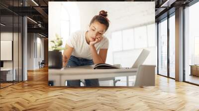 Hardworking woman working on her designer collection looking through a fashion magazine to find inspiration. Wall mural