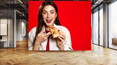 Portrait of smiling vegetarian woman holds vegan pizza slice, eats takeaway fastfood, order delivery in restaurant app, red background Wall mural