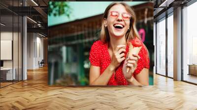 Tropical vacation. Happy young woman traveller laughing, eating ice cream on summer streets of paradise resort, enjoying warm climate, standing in sunglasses and dress Wall mural