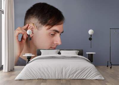 A young man is wearing a hearing aid. ENT equipment concept  Wall mural