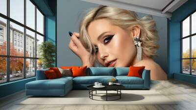 Portrait of young beautiful blond woman with evening make up touching her head. Modern fashion eyeliner wing and beautiful earring. Studio shot. Wall mural