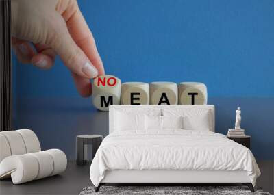 Man turns a wooden cube and form the expression 'eat no meat'. Beautiful grey table blue background Wall mural