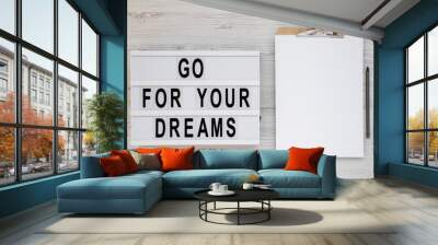 'Go for your dreams' words on a lightbox, clipboard with blank sheet of paper on a white wooden background, top view. Overhead, from above, flat lay. Copy space. Wall mural