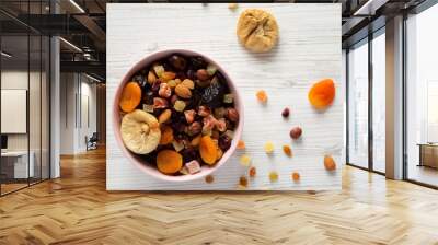 Dried fruits and nut mix in a pink bowl on white wooden background, top view. Overhead, from above, overhead. Wall mural