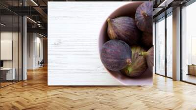 Fresh figs in a pink bowl over white wooden surface, overhead view. Top view, flat lay, from above. Copy space. Wall mural