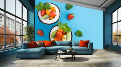 Fruit  salad in the  half coconut on the blue background. Top view.Copy space. Wall mural