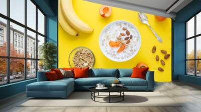 Granola breakfast with milk, fruits and almonds in the white bowl on the yellow background. Top view. Closeup. Wall mural