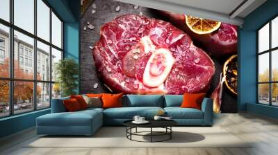 Raw ossobuco meat, beef steak with spices and salt for cooking, black stone concrete background, a traditional dish of Italian cuisine, which is a veal shank. Wall mural