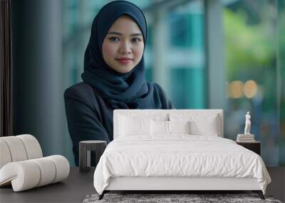 Young happy and successful South East Asian Islamic business woman with arms crossed in business corporate building setting looks at camera Wall mural