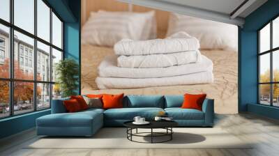 Stack of white hotel towel on bed in bedroom interior. Wall mural