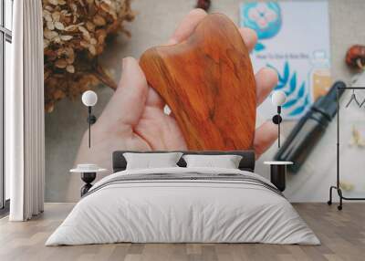 Scraper gua sha on hand, close up massage tool, wooden scraper for skin, skin care with guasha Wall mural