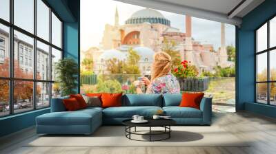 Girl drinks Turkish coffee enjoying the view of the Hagia Sophia Museum. Wall mural