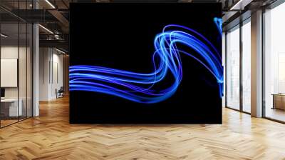 Blue light painting photography, long exposure, blue streaks of vibrant color against a black background Wall mural