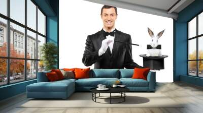 A magician in a black suit holding a top hat with a rabbit in it Wall mural