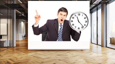 angry businessman sitting and holding a wall clock Wall mural