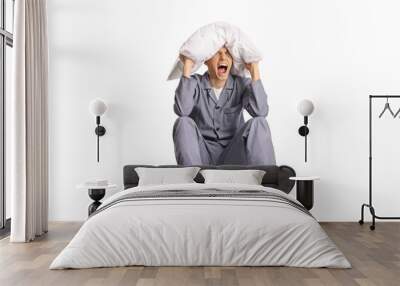 Angry young man in pajamas screaming and holding pillow over head Wall mural