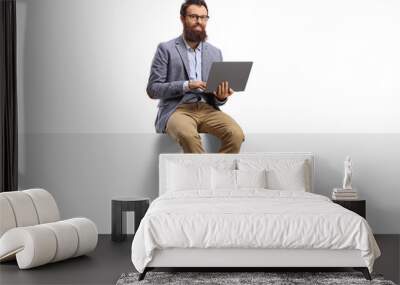 Bearded man working on a laptop and sitting on a banner Wall mural