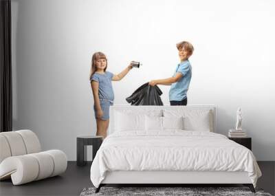 Boy holding a plastic waste bag and girl throwing a tin can Wall mural