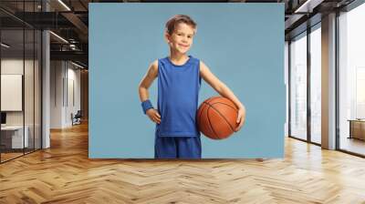 Boy in a blue jersey holding a basketball isolated on blue Wall mural