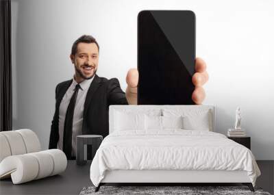 Businessman holding a smartphone and in front of camera and smiling Wall mural