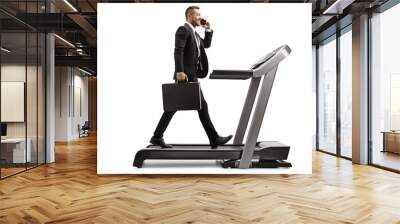 Businessman with a briefcase talking on a mobile phone and walking on a treadmill Wall mural