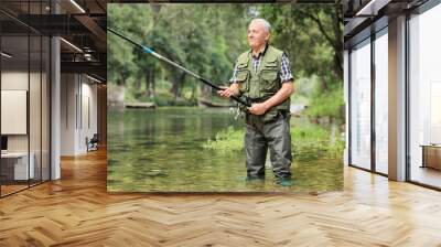 Cheerful mature fisherman fishing in a river Wall mural