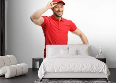 Delivery man with a box smiling and greeting with cap Wall mural