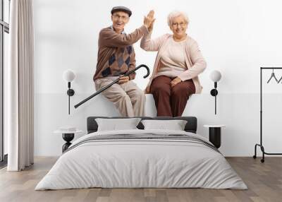 Elderly man and woman seated on panel high-fiving each other Wall mural