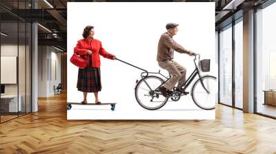 Elderly man on a bicycle pulling an elderly woman on a longboard Wall mural