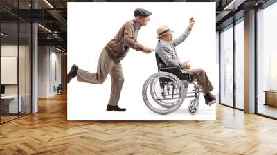 Elderly man riding a longboard and pushing a man in a wheelchair Wall mural