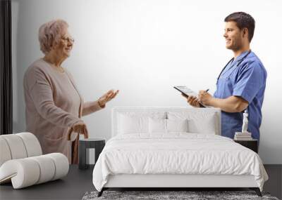 Elderly woman talking to a young male doctor in a blue uniform Wall mural