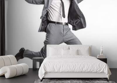 Excited young businessman in a grey suit jumping Wall mural