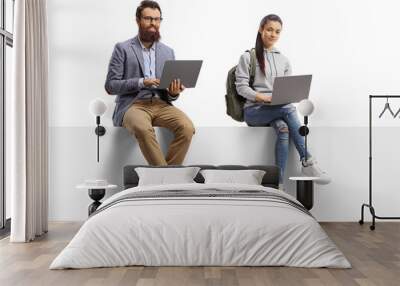 Female student and a bearded man sitting on a blank board and using laptop computers Wall mural