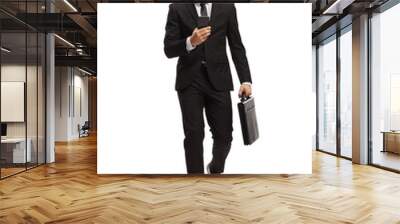 Full length portrait of a young businessman walking and typing on a smartphone Wall mural