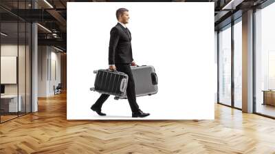 Full length profile shot of a businessman in a suit walking and carrying suitcases Wall mural