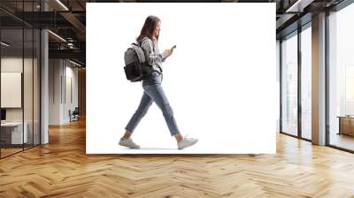 Full length profile shot of a female student walking with a mobile phone Wall mural