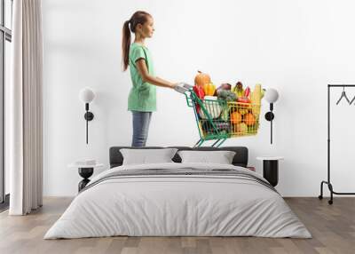 Full length profile shot of a girl waiting with a full shopping cart Wall mural