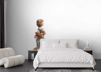 Full length profile shot of a little girl walking and carrying a teddy bear Wall mural