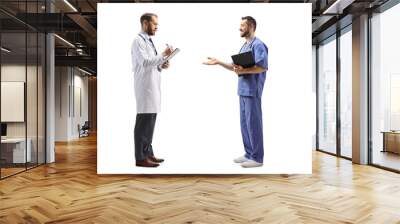 Full length profile shot of a male doctor standing and writing a document and talking to a healthcare worker Wall mural