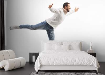 Full length profile shot of a man in jeans and white knitwear performing ice skating Wall mural