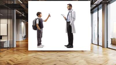 Full length profile shot of a schoolboy standing and showing a mobile phone to a male pediatrician doctor Wall mural