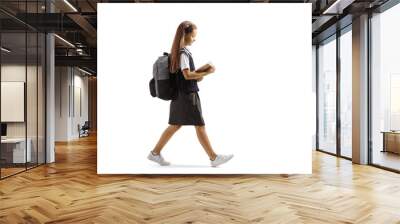 Full length profile shot of a schoolgirl walking and reading a book Wall mural