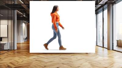 Full length profile shot of a young female in jeans and sweatshirt walking Wall mural