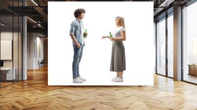 Full length profile shot of a young man and woman holding bottles of beer and talking Wall mural