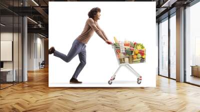 Full length profile shot of a young man running with a shopping cart Wall mural