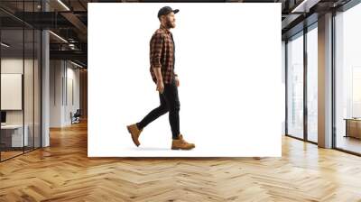 Full length profile shot of a young trendy man in a shirt and cap walking Wall mural